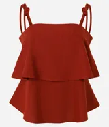 Blusa femenina color azul marino, sin mangas, con breteles anchos que tienen nudos decorativos y escote recto. Presenta capas sobrepuestas en la parte delantera que crean un leve volumen.