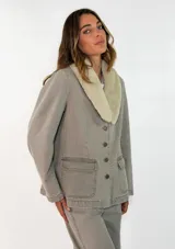 Chaqueta de denim color gris con cuello de piel sintética en tono crema, cierre frontal con botones metálicos y bolsillos frontales tipo cargo.