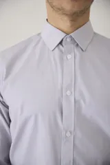 Camisa de vestir blanca de manga larga, con cuello clásico y cierre frontal de botones. Presenta un corte entallado que se adapta a la silueta.