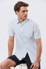Camisa de manga corta de algodón en color celeste con microdiseño geométrico a cuadros, cuello camisero y bolsillo frontal con logo bordado.