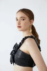 Top corto de cuero sintético negro con breteles fruncidos con elástico y volado central. Espalda unida por tiras elastizadas y fruncidas.