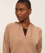 Campera deportiva color beige, con cierre frontal y capucha ajustable con cordón.