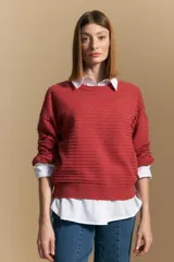 Sweater color crema con mangas abullonadas y puños elastizados. Presenta una textura tejida en relieve con patrón de ladrillos en el cuerpo y rayas horizontales en las mangas.