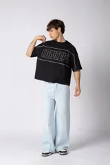 Remera gris oscuro de corte boxy, con mangas cortas y cuello redondo. Cuenta con un diseño gráfico frontal con líneas blancas y la palabra 'CONCEPT' estampada.