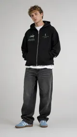 Campera con capucha negra, corte boxy, cierre frontal de cremallera metálica, bolsillos tipo canguro y pequeños estampados en tono verde claro en el pecho.