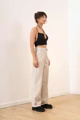 Pantalón de cuero sintético negro, de corte ancho, con bolsillos laterales y ruedo con dobladillo.