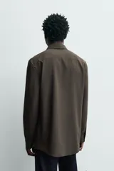 Camisa slim fit de color marrón oscuro, con cuello italiano, manga larga con puños abotonados y cierre frontal de botones. Confeccionada en tejido de fácil cuidado que minimiza la necesidad de planchado.
