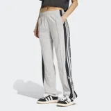 Pantalón deportivo Adidas Adibreak de color gris, con franjas negras laterales y las clásicas tres tiras blancas. Cuenta con botones a presión en los laterales, cintura elástica y diseño holgado.