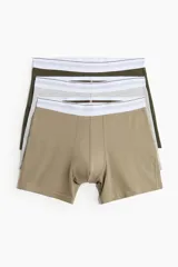 Pack de tres calzoncillos tipo trunk, confeccionados en punto elástico de algodón con tecnología Lycra® Xtra Life™. Incluye un par en color caqui, uno gris jaspeado y uno verde oliva, todos con cintura elástica blanca con franjas grises y verdes.