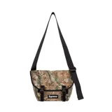 Bolso tipo messenger de Supreme con estampado de camuflaje forestal. Cuenta con solapa frontal con cierre de hebillas, correa ajustable para el hombro y logo de la marca en la parte inferior.