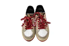 Zapatillas casual Arizona Love con base color beige, puntera blanca y detalles de tela estampada con motivos de leopardo y flores. Cordones gruesos rojos con cuentas de colores.