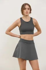 Top deportivo de sujeción media con escote redondo y espalda abierta. Presenta un diseño al cuerpo con elástico oculto en la cintura.