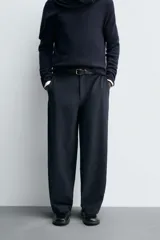 Pantalón de corte balloon fit, color negro, con bolsillos laterales de vivo y bolsillos traseros con solapa. Presenta cierre frontal con cremallera y botón.