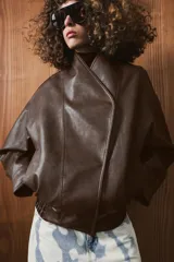 Chaqueta bomber de efecto piel en color marrón oscuro, con cuello subido, cierre frontal cruzado con botones a presión, bolsillos laterales y bajo elástico.