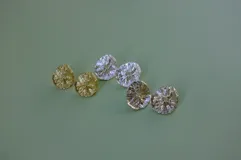 Aros tipo botón dorados con textura irregular que simula la superficie de un molusco.