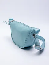 Riñonera semicircular color celeste de nylon con correa regulable, cierre superior y elásticos en los laterales.