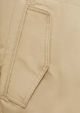 Campera color beige, tipo anorak, con cuello camisero, cierre frontal con botones, manga larga con trabillas, diseño oversize y forro interior.