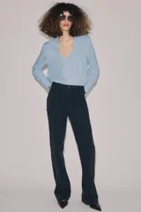 Jeans de tiro alto con corte flare y diseño de rayas verticales. Presenta cintura con trabillas, falsos bolsillos delanteros con solapa y botón, y cierre frontal con cremallera y botón.