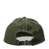 Gorra tipo snapback color negro con costuras blancas visibles y parche rectangular beige con logo de la marca en el frente.