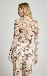 Blusa de manga larga confeccionada en tul semitransparente con estampado abstracto en tonos marrones y beige, cuello redondo y calce ajustado.