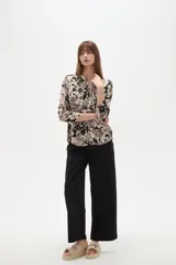 Camisa holgada de viscosa con cuello mao, mangas largas y estampado floral en tonos beige, marrón y negro, con dos bolsillos frontales con solapa.
