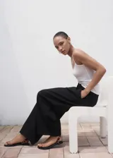 Pantalón wide leg de tiro medio color negro, con diseño largo, bolsillos laterales, bolsillos de ribete posteriores y detalle de pinzas. Cuenta con cierre oculto de botón, gancho y cremallera, e incluye forro interior.