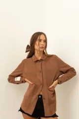 Camisa marrón de corte recto con botones y bolsillos frontales.