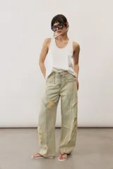 Pantalón de jean de corte wide leg, tiro medio y lavado claro con efecto desgastado. Presenta diseño de múltiples paneles con costuras pespunteadas verticales y roturas en ambas piernas.