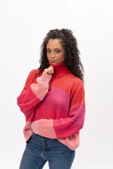 Buzo de tejido de punto con diseño a rayas horizontales en tonos degradados de rojo y rosa. Presenta cuello alto con cierre frontal parcial, mangas largas y corte holgado.
