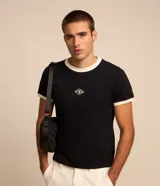 Remera negra de algodón, modelo baby tee de manga corta, con cuello redondo y ribetes en color blanco. Presenta un pequeño tag gomoso con la inscripción "Lucky" en el centro del pecho.