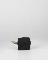 Monedero pequeño de color negro con cierre superior y una tira lateral beige con mosquetón metálico. Incluye una etiqueta con la inscripción de la marca en la parte superior.