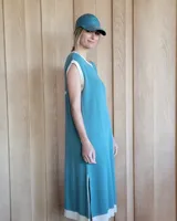 Vestido largo color lila, sin mangas, con cuello redondo y una gran estrella blanca estampada en la espalda. El cuello y el dobladillo inferior son de color beige.