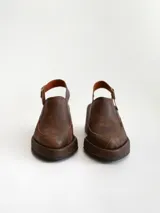 Zapato tipo zueco de cuero color chocolate con efecto desgastado, plataforma y taco cuadrado. Presenta una tira trasera ajustable con hebilla metálica.