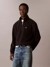 Buzo de felpa negro con cuello alto tipo mock y cierre de cremallera de un cuarto. Presenta el logo Archive de Calvin Klein bordado en el pecho, puños y bajo acanalados.