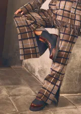 Pantalón de lana a cuadros color beige y blanco, entallado hasta la rodilla y con caída amplia tipo oxford, tajos laterales, elástico en la cintura y cierre oculto.