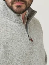 Buzo polar de hombre con cuello alto y medio cierre frontal. Presenta un diseño de tejido jaspeado en tonos grises, manga larga y calce regular.