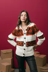 Saco tejido a mano con diseño jacquard, de corte recto y largo a la cadera. Presenta cuello redondo, cierre frontal con botones y mangas largas. Incluye tajos laterales en el ruedo.