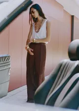 Pantalón de tiro medio en tejido satinado con efecto arrugado y diseño recto. Cuenta con bolsillos laterales, pinzas delanteras y cierre oculto con botón, gancho y cremallera.