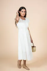 Vestido midi blanco de corte recto con escote redondeado y detalle de frunces. Tiene lazo en la cintura para ajustar la silueta y mangas cortas.