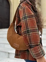 Sobrecamisa de corte holgado con estampado a cuadros en tonos terracota, marrón y verde. Presenta cuello clásico, cierre frontal con botones y mangas largas con puños abotonados.