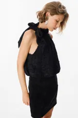 Blusa blanca sin mangas con cuello halter y lazo lateral. Confeccionada en tela de gasa con textura floreada en relieve.