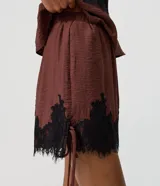 Short marrón de viscosa con calce suelto, cintura elástica y detalle de encaje floral negro en el ruedo. Cuenta con amarras laterales ajustables.