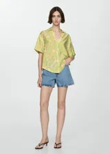 Camisa de manga corta con estampado floral en tonos verde y amarillo. Diseño oversize con cuello camisero y cierre frontal con botones.