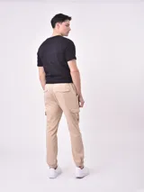Pantalón jogger negro con cintura elástica y cordón ajustable, bolsillos laterales y bolsillos cargo con solapa en los muslos. Los tobillos tienen puños elásticos.