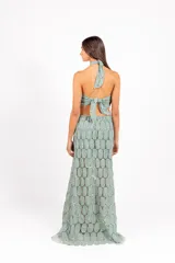 Vestido largo de encaje con patrón circular, color lila, de corte halter con tiras cruzadas al cuello y aberturas laterales en la cintura.
