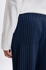 Pantalón de corte recto y tiro medio, confeccionado en tela azul oscuro con estampado de rayas verticales finas en color blanco. Presenta cintura elástica con cordón ajustable y bolsillos laterales.
