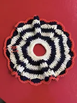 Gomita de pelo tejida a crochet con hilo de algodón a rayas horizontales en color azul marino y blanco, con borde tejido en color coral.