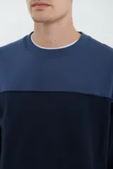 Sweater deportivo de hombre con escote redondo, diseño colorblock con la parte superior en gris claro y el cuerpo y mangas en negro. Presenta puños y cintura elastizados.