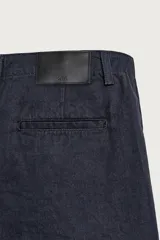 Bermuda de denim color azul marino, de corte relaxed fit con pliegues frontales, bolsillos laterales y cierre frontal con cremallera y botón.