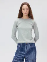 Remera de manga larga con cuello a la base, confeccionada en tejido de punto acanalado color beige. Presenta un logo bordado en el centro del pecho.